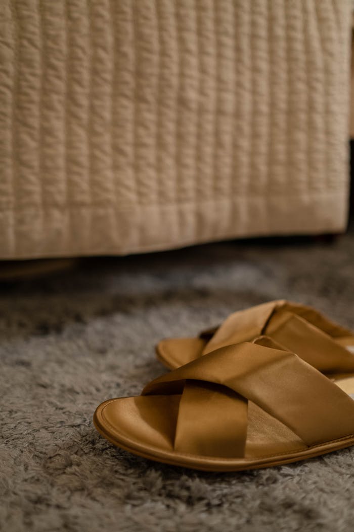 Cozy brown slippers placed on a soft bedroom carpet for a relaxed at-home vibe.